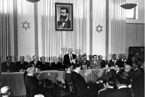 David Ben-Gurion declaring Israel’s independence, under a portrait of Theodor Herzl.